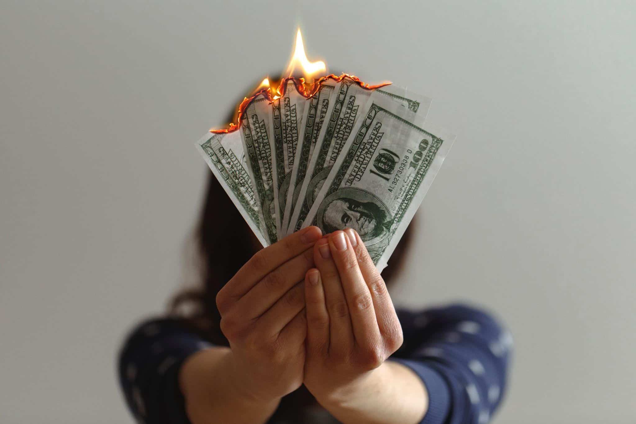 Young woman lighting several dollar bills on fire