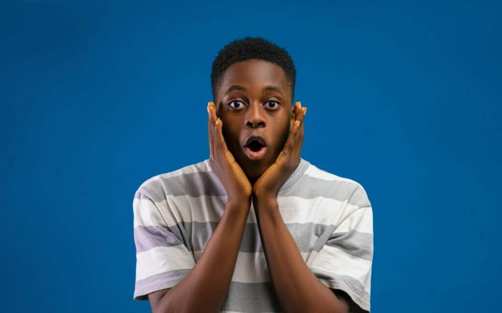 recession A young man with a shocked expression and hands on his cheeks