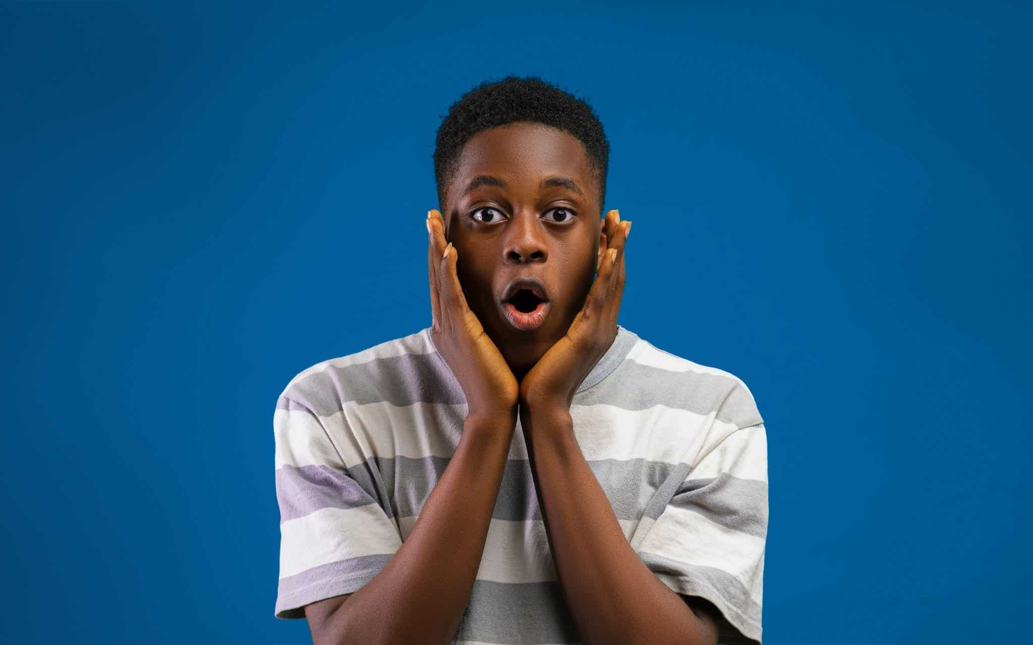 recession A young man with a shocked expression and hands on his cheeks