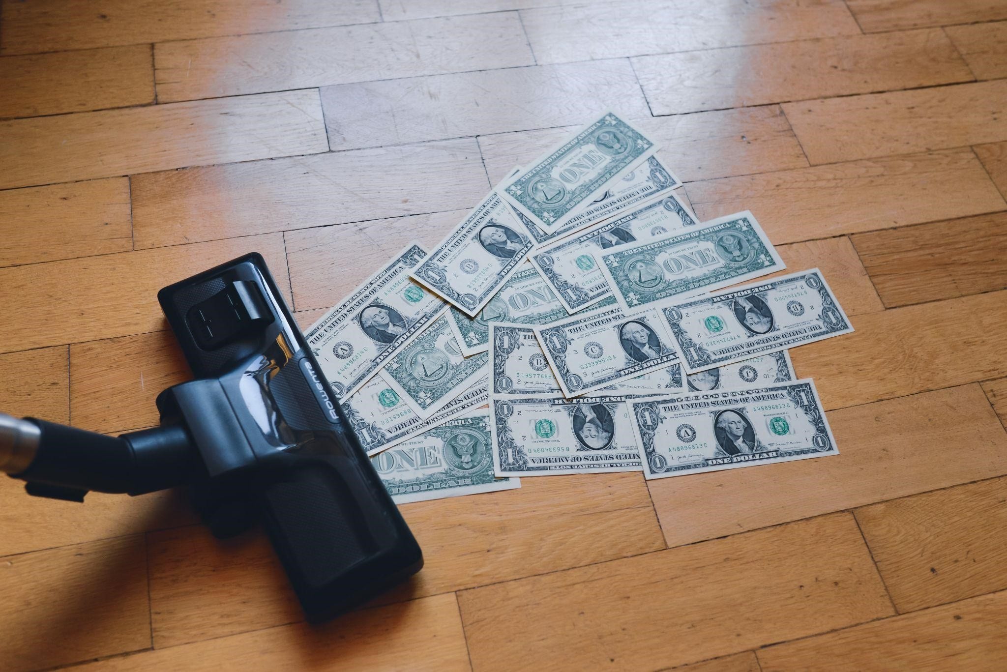 A vacuum cleaner sucking up dollar bills, representing the devaluation of money